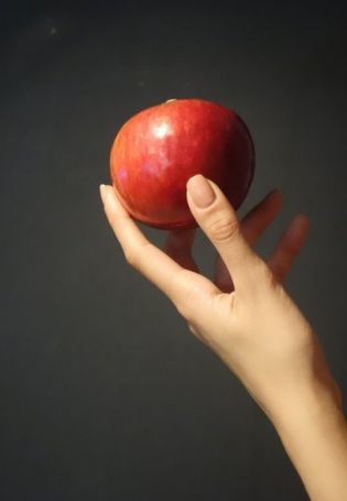 Рука держит яблоко