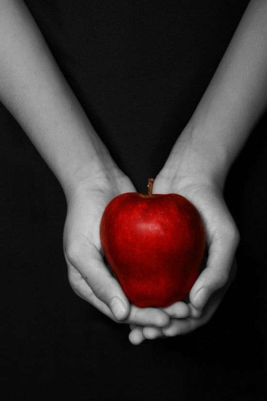 Яблоко в руке на черном фоне