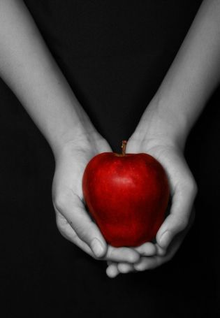 Яблоко в руке на черном фоне