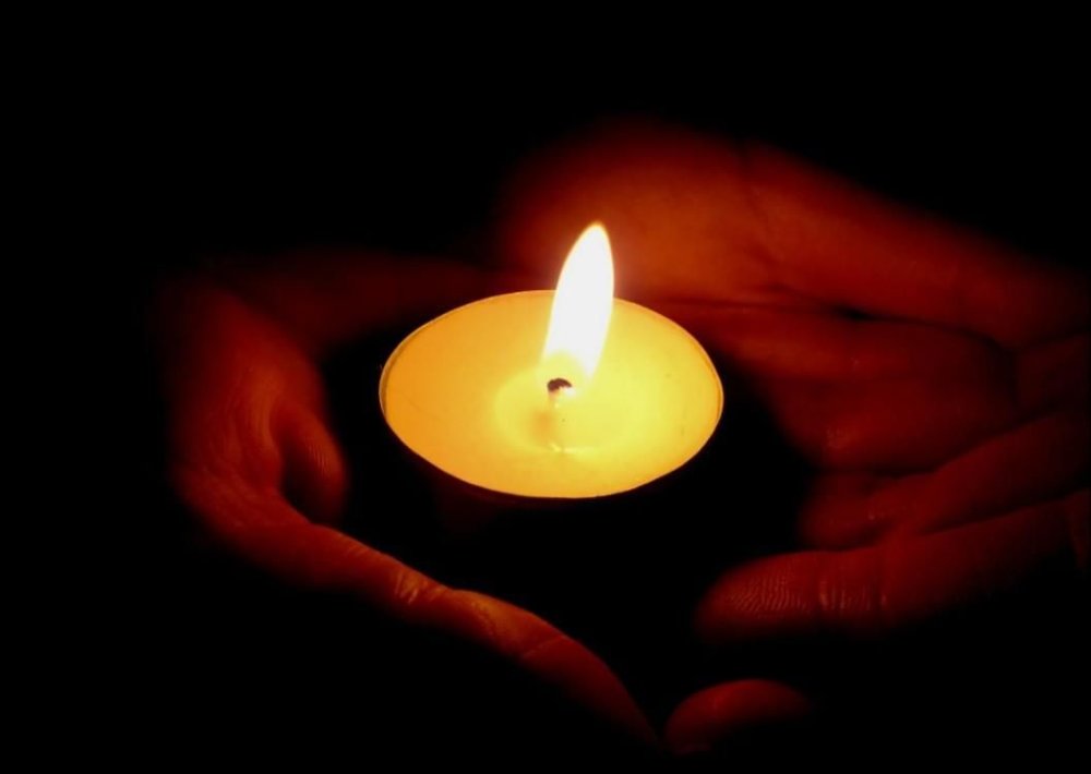 Свеча в руках в темноте