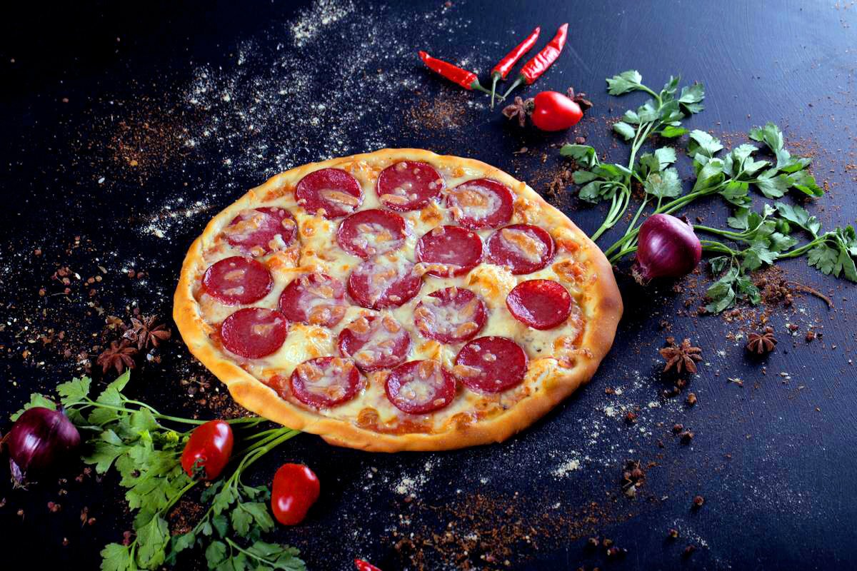 Пицца пепперони на черном фоне