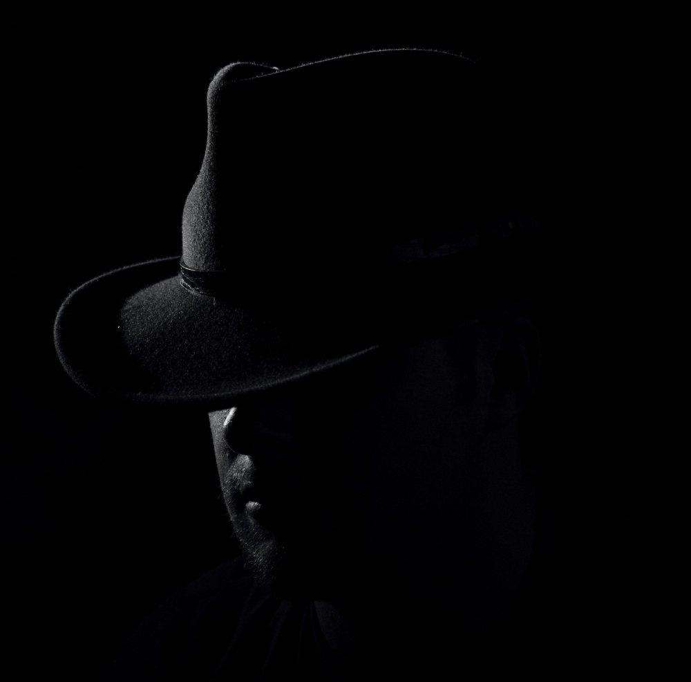 Мужчина в шляпе на черном фоне