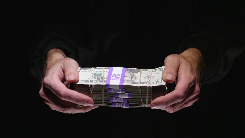 Рука с деньгами на черном фоне