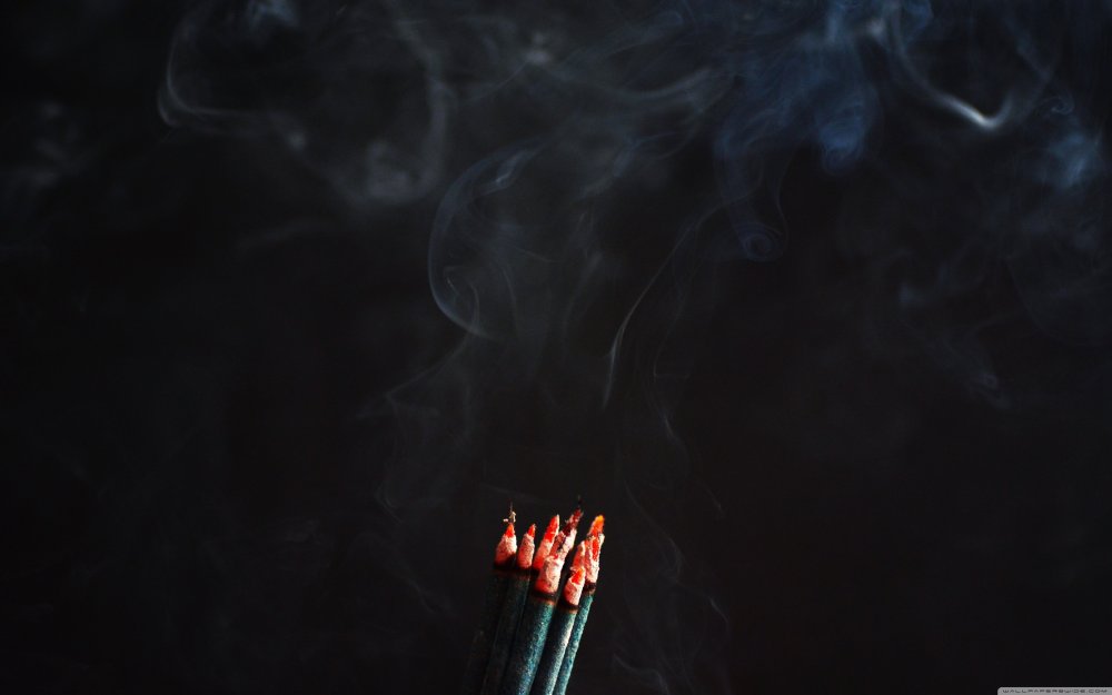 Дымящая сигарета на темном фоне огня