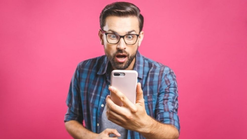 Удивленное лицо мужчины с телефоном