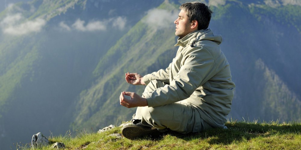 Мужчина медитирует в горах